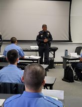 Image of new recruit class in a classroom with Chief Scott